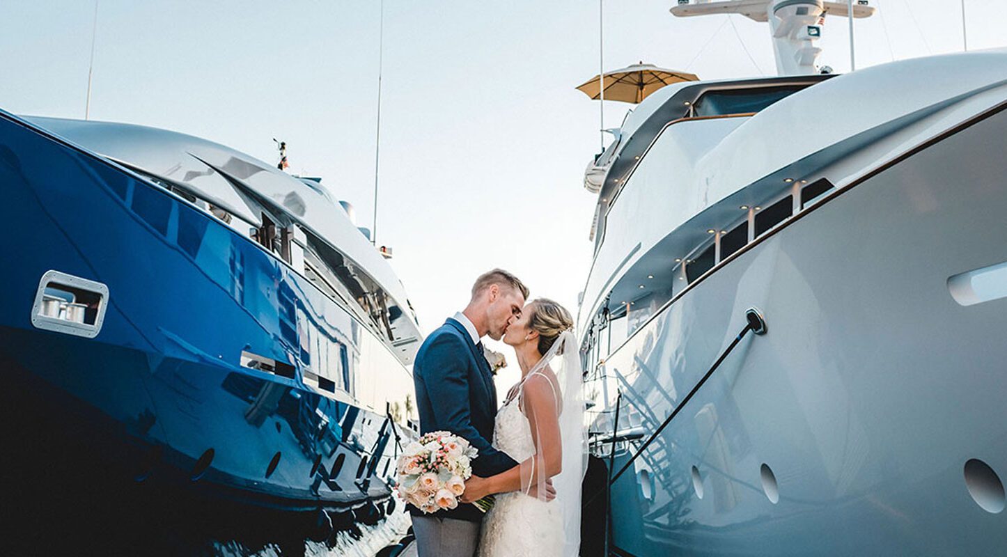 bride and groom kissing between two yachts